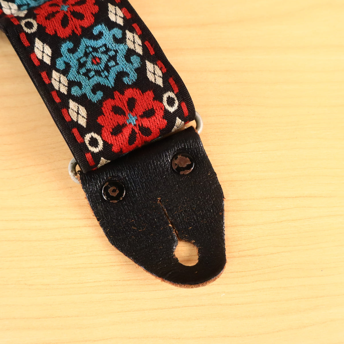 Close-up of black leather strap end tab with metal rivets.