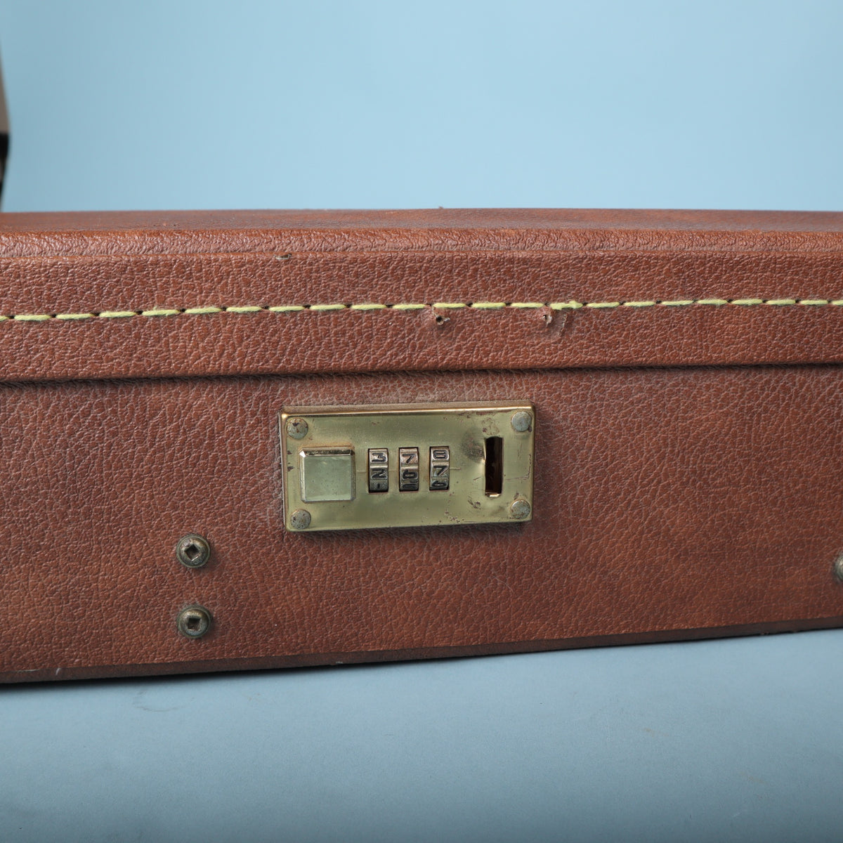 Detail of the brass-finish three-digit combination lock on the side of the Gibson case