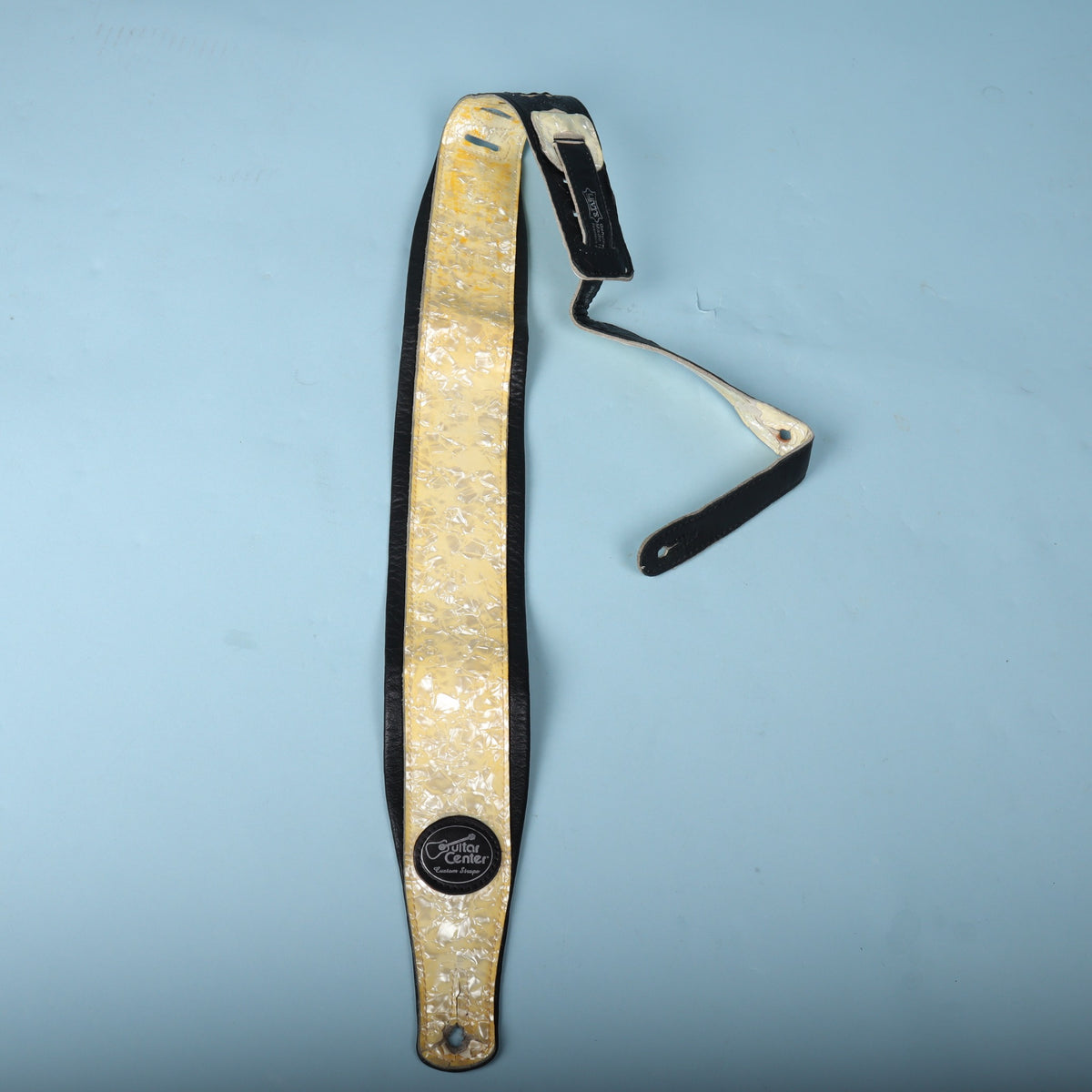 Full view of the strap laid out lengthwise showing the pearloid top and black leather body.