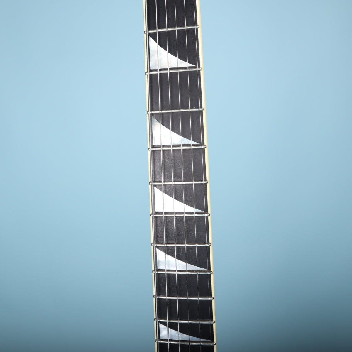 Close-up of the bound ebony fretboard featuring mother-of-pearl sharkfin inlays