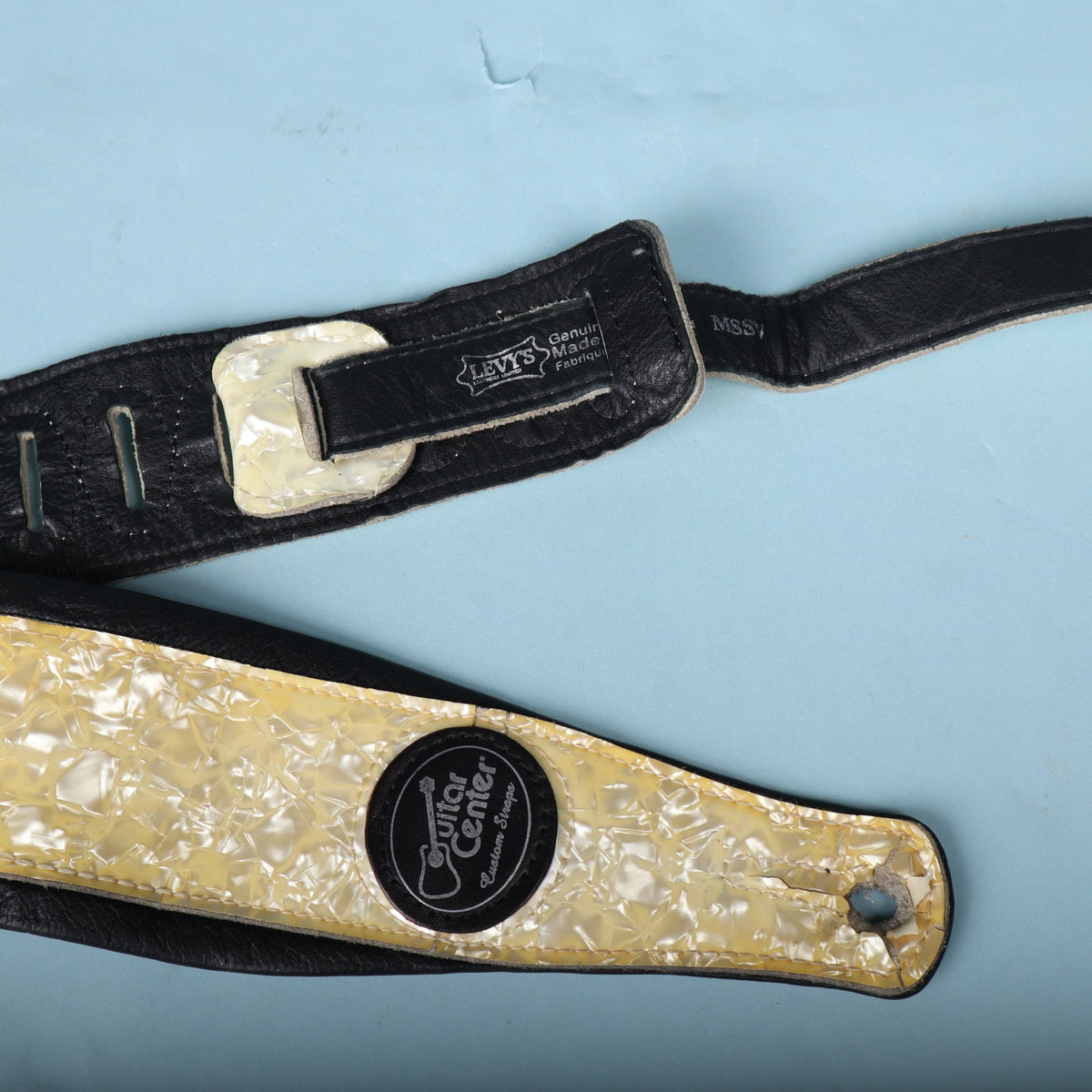 Close-up showing the feed-through loop, stamped brand tag, and lower end of the strap.