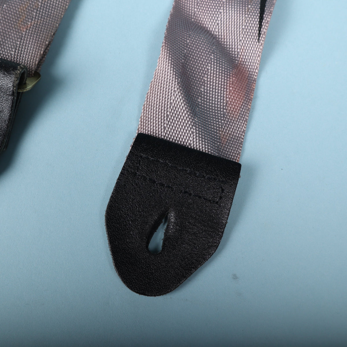 Close-up of the black leather strap end showing stitching and button hole slit.