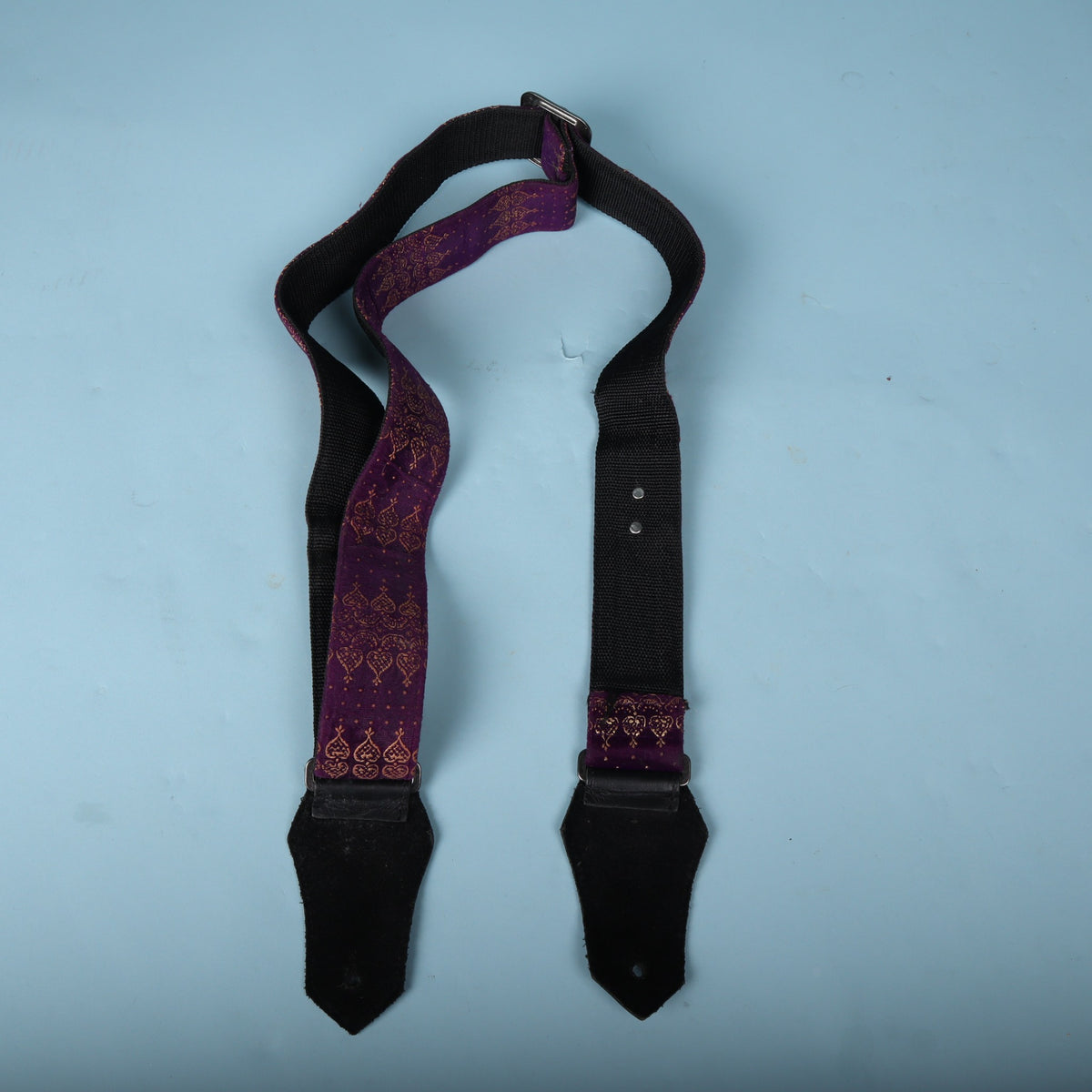 Full back view of the strap laid out against a blue background