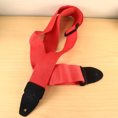 Overview of the red 2-inch strap loosely coiled on a wooden surface.