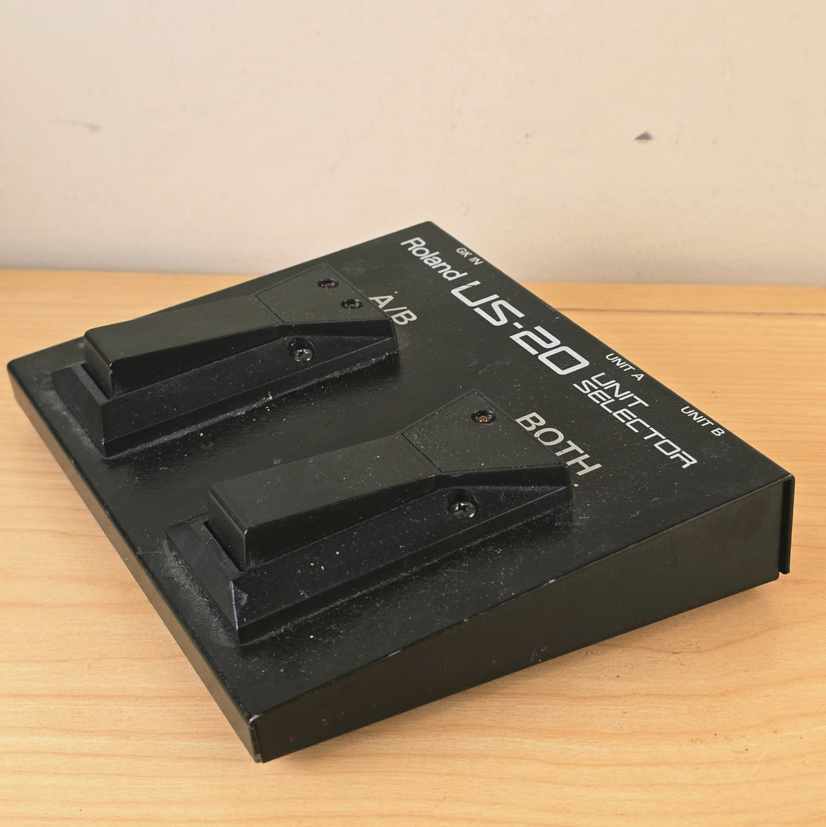 Angled side view of the Roland US-20 dual footswitch unit on a wooden surface.
