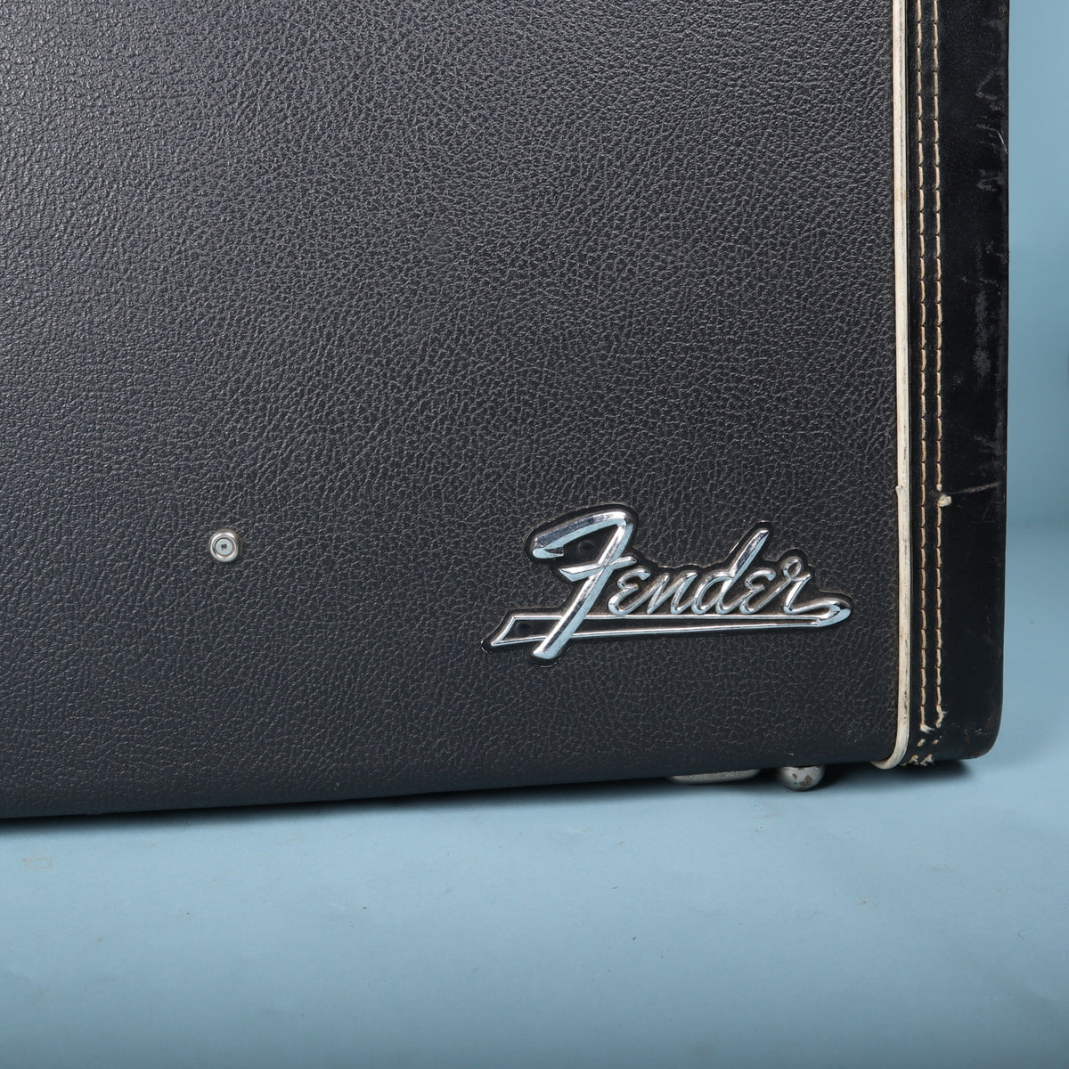 Close-up of chrome Fender script logo on black hardshell case