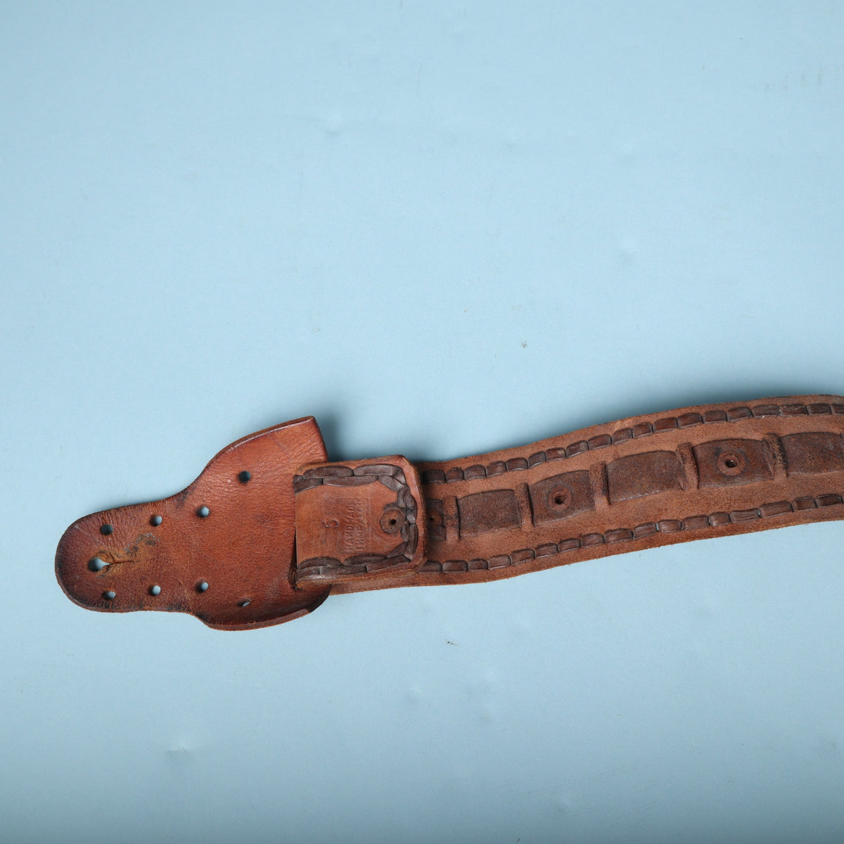 Strap button end tab connected to main laced leather body