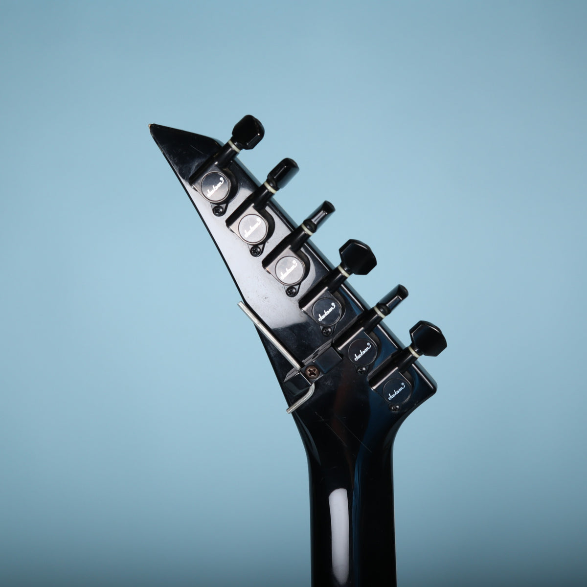 Rear close-up of the headstock showing six-in-line Jackson tuners and wrench bracket