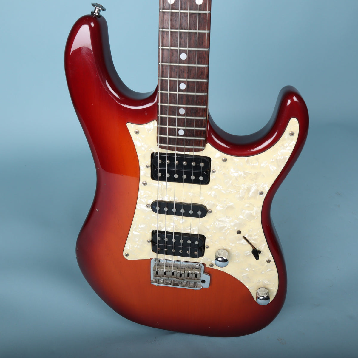 Front body detail showing pearloid pickguard, humbuckers, single coil pickup, and knobs.