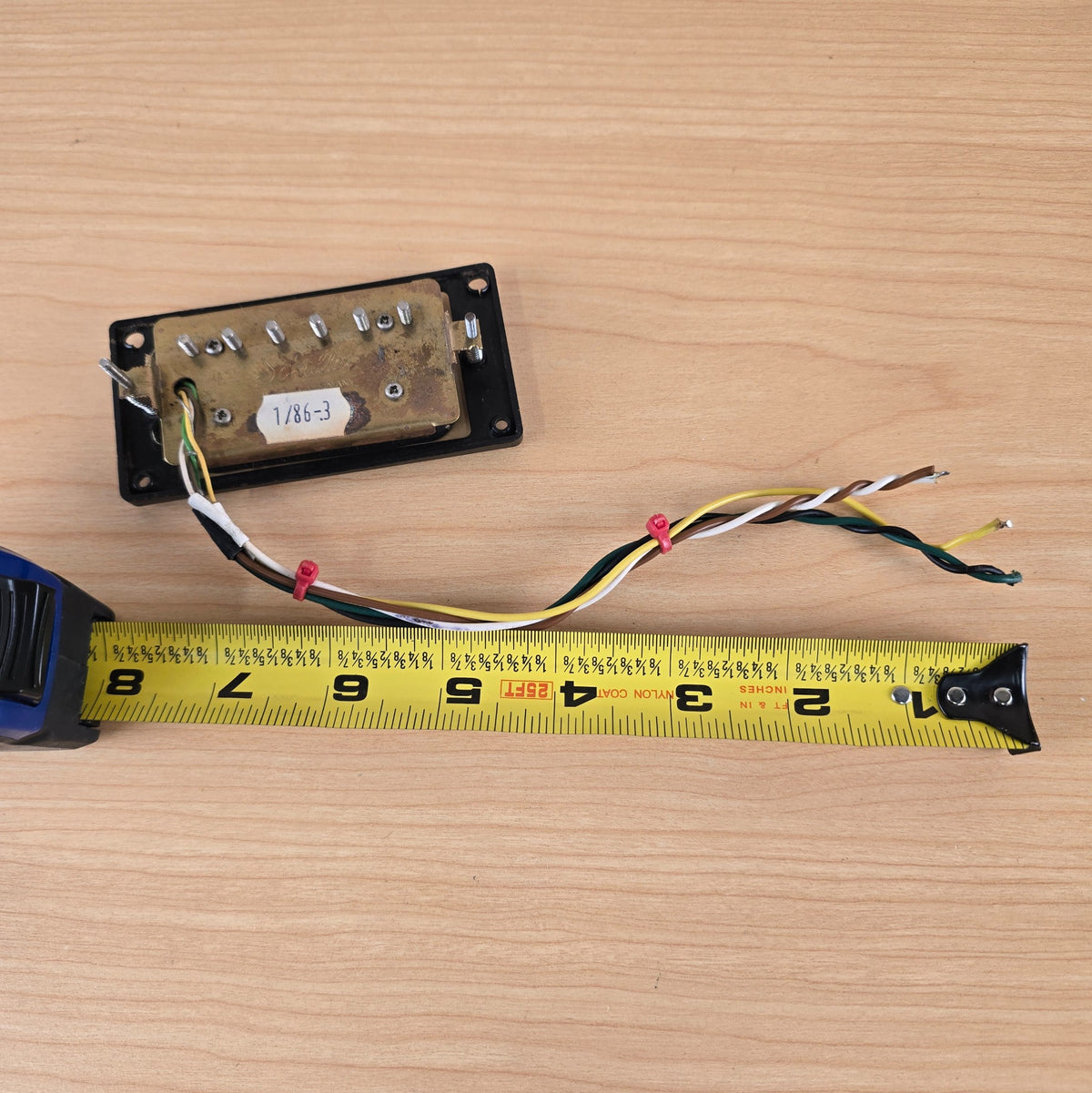 Schaller humbucker baseplate measured with tape measure displaying approximately six to seven inches of wire lead