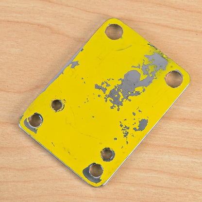 Back side of the Danelectro neck plate showing peeling yellow backing material and metal finish.