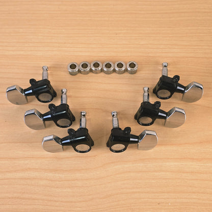 Top-down view of six black and chrome Schaller guitar tuning machines and bushings