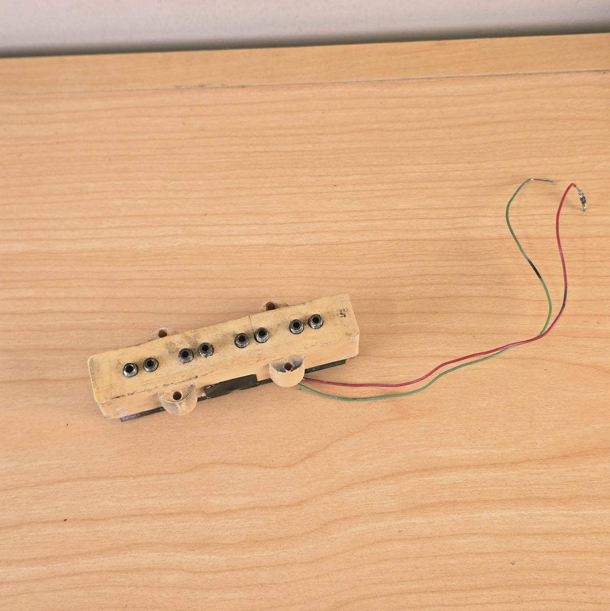 Top view of a cream 4-string bass pickup with green and red lead wires.