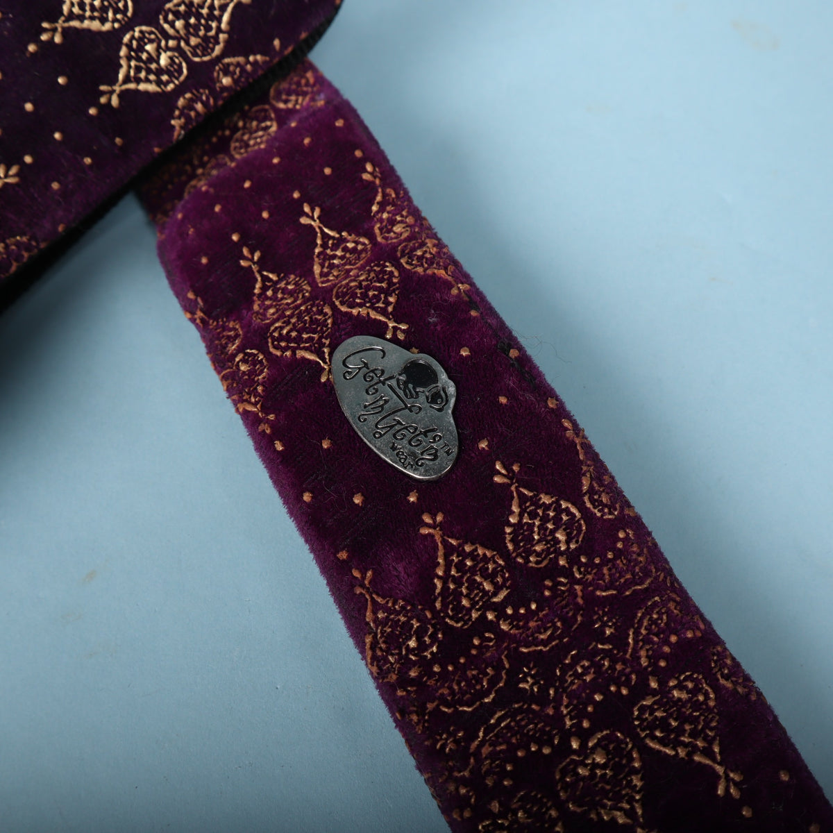 Close-up of the cast metal Get'm Get'm badge pinned to the purple velvet