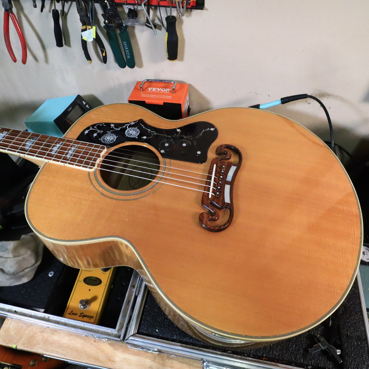 Front perspective view of Gibson J-200 resting on a service bench.