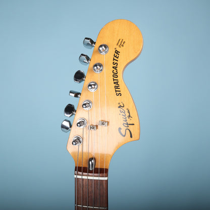 Front view of headstock with Squier Stratocaster headstock logo on blue background.